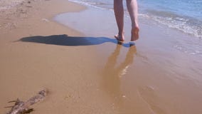 Barefooted woman tourist walks in water on sea sand beach, legs closeup. stock video Barefooted woman tourist walks in water on sea sand beach, legs closeup. stock video