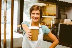 Barista grazioso che sorride alla macchina fotografica che tiene tazza eliminabile fotografie stock libere da diritti Barista grazioso che sorride alla macchina fotografica che tiene tazza eliminabile fotografie stock libere da diritti