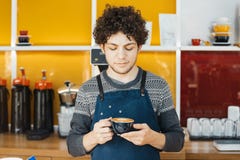 Barista que sostiene la taza de café cerca de contador de la barra en café moderno brillante fotografía de archivo libre de regalías Barista que sostiene la taza de café cerca de contador de la barra en café moderno brillante fotografía de archivo libre de regalías
