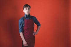 Barista с темными волосами в красной рисберме смотря камеру и держа руку на бедре на предпосылке цвета коралла стоковая фотография Barista с темными волосами в красной рисберме смотря камеру и держа руку на бедре на предпосылке цвета коралла стоковая фотография