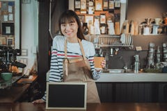 Barman asiatique de sourire tenant la tasse de café à la contre- barre avec photo libre de droits Barman asiatique de sourire tenant la tasse de café à la contre- barre avec photo libre de droits