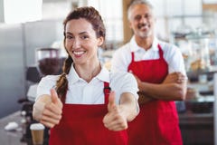 Barman de sourire faisant des gestes des pouces avec le collègue derrière Images libres de droits Barman de sourire faisant des gestes des pouces avec le collègue derrière Images libres de droits