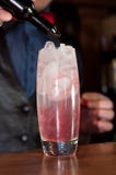 Barmanu dolewania czerwony syrop od butelki w szkło z alkoholu lodem i napojem obraz stock Barmanu dolewania czerwony syrop od butelki w szkło z alkoholu lodem i napojem obraz stock