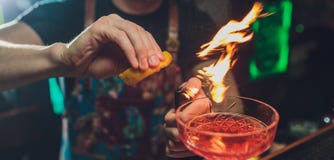 Barmanu s ręki robi świeżemu alkoholicznemu koktajlowi z dymiącą notatką na zmroku baru kontuarze obrazy stock Barmanu s ręki robi świeżemu alkoholicznemu koktajlowi z dymiącą notatką na zmroku baru kontuarze obrazy stock
