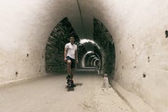 Barn 20-25 år gamal man i tunnel med skateboarden Omgivande lig royaltyfria bilder Barn 20-25 år gamal man i tunnel med skateboarden Omgivande lig royaltyfria bilder