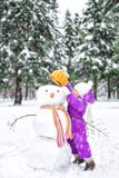 Barnet hugger en snögubbe i snö-täckt parkerar Utomhus- aktiviteter för vinter fotografering för bildbyråer Barnet hugger en snögubbe i snö-täckt parkerar Utomhus- aktiviteter för vinter fotografering för bildbyråer