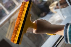 Barns hand tvättar fönstret med en torkare royaltyfria foton Barns hand tvättar fönstret med en torkare royaltyfria foton