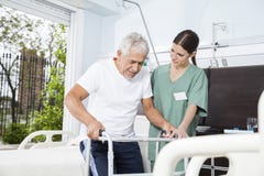 Barnsjuksköterska Helping Patient In som använder Walker At Nursing Home arkivfoto Barnsjuksköterska Helping Patient In som använder Walker At Nursing Home arkivfoto