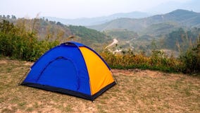 Barraca de acampamento azul e amarela do turista na área de recreação entre o prado na floresta da montanha fotografia de stock Barraca de acampamento azul e amarela do turista na área de recreação entre o prado na floresta da montanha fotografia de stock