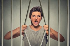 Barre di piegamento della donna arrabbiata disperata della sua cella di prigione fotografie stock Barre di piegamento della donna arrabbiata disperata della sua cella di prigione fotografie stock