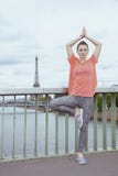 Basculador da mulher não longe da torre Eiffel que faz a ioga foto de stock Basculador da mulher não longe da torre Eiffel que faz a ioga foto de stock