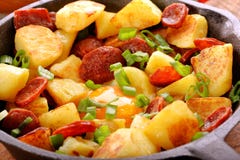 Batatas cozidas com chouriço e ovo frito da salsicha na frigideira imagens de stock royalty free Batatas cozidas com chouriço e ovo frito da salsicha na frigideira imagens de stock royalty free