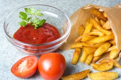 Batatas fritas, batatas fritadas com ketchup e tomates no fundo do granito cinzento-azul fotografia de stock Batatas fritas, batatas fritadas com ketchup e tomates no fundo do granito cinzento-azul fotografia de stock