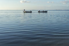 Bateaux de pêche qui croisent à l'aube avec la mer calme photo stock Bateaux de pêche qui croisent à l'aube avec la mer calme photo stock
