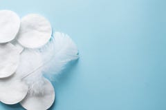 bawełniani ochraniacze z białym piórkiem na błękitnym tle zamykają w górę kosmos kopii Odgórny widok zdjęcia royalty free bawełniani ochraniacze z białym piórkiem na błękitnym tle zamykają w górę kosmos kopii Odgórny widok zdjęcia royalty free