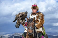 Kazakh man in traditional outfit with his eagle on a horse stock image Kazakh man in traditional outfit with his eagle on a horse stock image