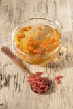 Bayas de Goji en una cuchara de madera y una taza de té con el berrie del goji fotos de archivo libres de regalías Bayas de Goji en una cuchara de madera y una taza de té con el berrie del goji fotos de archivo libres de regalías