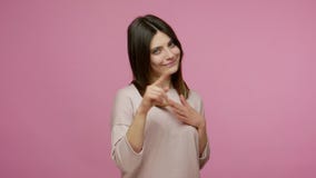 Be my Valentine! Charming playful brunette young woman expressing romantic feelings with heart hand gesture