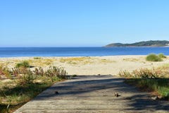 Beach with boardwalk, golden sand and vegetation in sand dunes. Blue sea, sunny day, Galicia, Spain. royalty free stock photo Beach with boardwalk, golden sand and vegetation in sand dunes. Blue sea, sunny day, Galicia, Spain. royalty free stock photo
