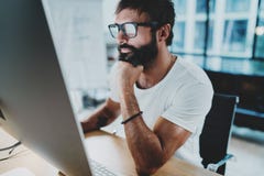 Bearded hipster professional wearing eye glasses working at modern loft studio-office with desktop computer.Panoramic royalty free stock photo Bearded hipster professional wearing eye glasses working at modern loft studio-office with desktop computer.Panoramic royalty free stock photo