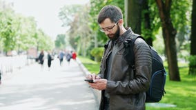 Bearded man with bag uses mobile phone on the street stock footage Bearded man with bag uses mobile phone on the street stock footage