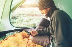 Bearded traveler Man uses his mobile phone sitting in tent stock image Bearded traveler Man uses his mobile phone sitting in tent stock image