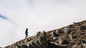 Bearded young male photographer in a hat and sunglasses and a camera around his neck climbs up the hill against the stock video Bearded young male photographer in a hat and sunglasses and a camera around his neck climbs up the hill against the stock video