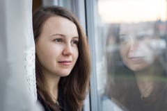 Beatiful young girl watching out of the window; looking from the stock photo Beatiful young girl watching out of the window; looking from the stock photo