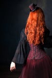 Beau dos de femme de steampunk Fille rousse mince dans le corset et le chapeau images libres de droits Beau dos de femme de steampunk Fille rousse mince dans le corset et le chapeau images libres de droits