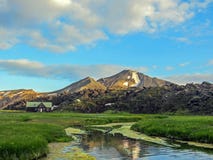 Beau paysage de région géothermique de Landmannalaugar avec la rivière, le champ d'herbe verte et les montagnes de rhyolite, Isla image libre de droits Beau paysage de région géothermique de Landmannalaugar avec la rivière, le champ d'herbe verte et les montagnes de rhyolite, Isla image libre de droits