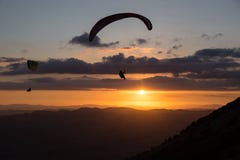 Beau tir de deux silhouettes de parapentiste volant au-dessus de Monte Cucco Umbria, Italie avec le coucher du soleil sur le fond Photographie stock libre de droits Beau tir de deux silhouettes de parapentiste volant au-dessus de Monte Cucco Umbria, Italie avec le coucher du soleil sur le fond Photographie stock libre de droits