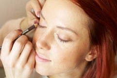 Beautician Is Doing Make-up To Red-haired Girl Stock Photo