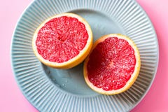Beautiful appetizer fresh red grapefruit citrus fruit with half slice on blue plate and pink background close up top view natural Stock Images Beautiful appetizer fresh red grapefruit citrus fruit with half slice on blue plate and pink background close up top view natural Stock Images