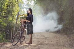 Beautiful Asian woman in local traditional dress with old bicycle and flower basket on the green summer field. royalty free stock photography Beautiful Asian woman in local traditional dress with old bicycle and flower basket on the green summer field. royalty free stock photography