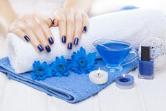 Beautiful blue manicure with chrysanthemum and towel on the white wooden table. spa