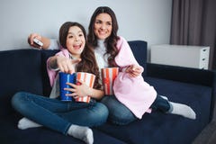 Beautiful brunette caucasian mother and daughter sit together in room. Emotional excited girl point forward. She hold stock image Beautiful brunette caucasian mother and daughter sit together in room. Emotional excited girl point forward. She hold stock image