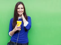 Beautiful brunette girl standing with a glass in his hand near the green wall and smiling at the camera stock images Beautiful brunette girl standing with a glass in his hand near the green wall and smiling at the camera stock images