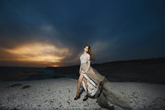 Beautiful Brunette Model Girl With Long Sexy Legs In Fashionable Lace Dress Posing At The Sea Coast At The Sunset With Royalty Free Stock Photography Beautiful Brunette Model Girl With Long Sexy Legs In Fashionable Lace Dress Posing At The Sea Coast At The Sunset With Royalty Free Stock Photography