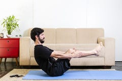 Beautiful caucasian bearded man in black clothes on blue yogamat doing boat pose stock photography Beautiful caucasian bearded man in black clothes on blue yogamat doing boat pose stock photography