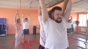 Beautiful caucasian female instructor teaches yoga techniques in a male group session. Strengthening muscle and health stock footage Beautiful caucasian female instructor teaches yoga techniques in a male group session. Strengthening muscle and health stock footage
