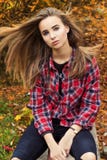 Beautiful charming young attractive girl with large blue eyes, with long dark hair in the autumn forest sits on a tree in black Stock Photography Beautiful charming young attractive girl with large blue eyes, with long dark hair in the autumn forest sits on a tree in black Stock Photography