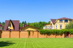 Beautiful country house with garage behind a brick fence. Summer stock photo Beautiful country house with garage behind a brick fence. Summer stock photo