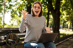 Beautiful excited happy woman outdoors sitting using laptop computer make okay gesture. stock photos Beautiful excited happy woman outdoors sitting using laptop computer make okay gesture. stock photos
