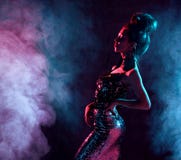 Beautiful fashion brunette woman posing in blue and pink neon light in fashion gold sparkle dress on dark royalty free stock photos Beautiful fashion brunette woman posing in blue and pink neon light in fashion gold sparkle dress on dark royalty free stock photos