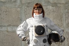 Beautiful girl astronaut without a helmet on the background of a gray wall. Fantastic space suit
