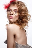 Beautiful girl in a gold dress with a gentle make-up. Model with red feathers on her head and curls. Holiday photo. stock image Beautiful girl in a gold dress with a gentle make-up. Model with red feathers on her head and curls. Holiday photo. stock image