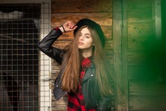 Beautiful girl with long hair and black hat, stands on the background of vintage old wooden house royalty free stock photography Beautiful girl with long hair and black hat, stands on the background of vintage old wooden house royalty free stock photography