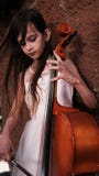 Beautiful girl in a pink dress stands with a cello