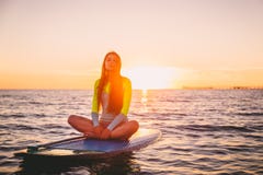 Beautiful girl relaxing on stand up paddle board, on a quiet sea with warm sunset colors. stock image Beautiful girl relaxing on stand up paddle board, on a quiet sea with warm sunset colors. stock image
