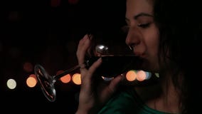 Beautiful girl takes glass of red wine over night background